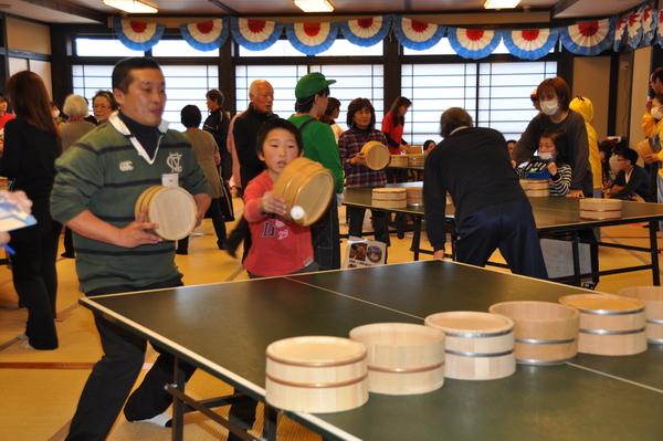 お父さんと息子の親子ペアの参加者が桶を持って卓球をしている写真