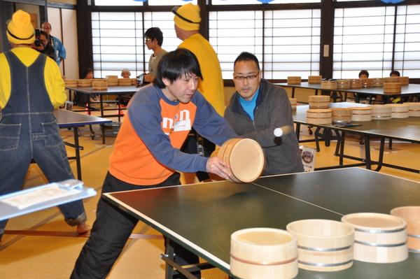 メガネをかけた男性とオレンジのトレーナーを着た男性2人の参加者が桶を持って卓球をしている写真