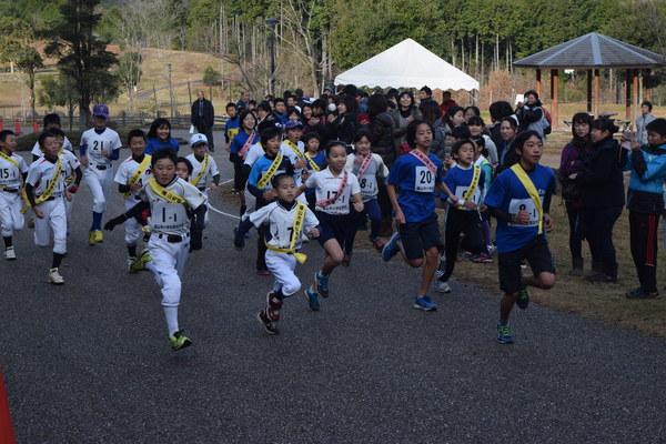 野球のユニフォームを着た子供達と青いシャツに紺の短パンをはいた子供達が一生懸命走っている写真