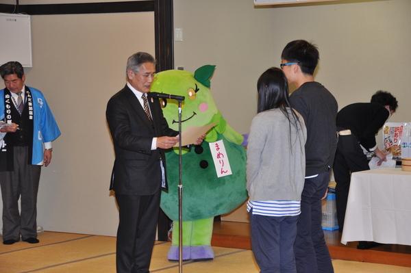 男女ペアの参加者がスーツを着た男性から表彰を受けている写真