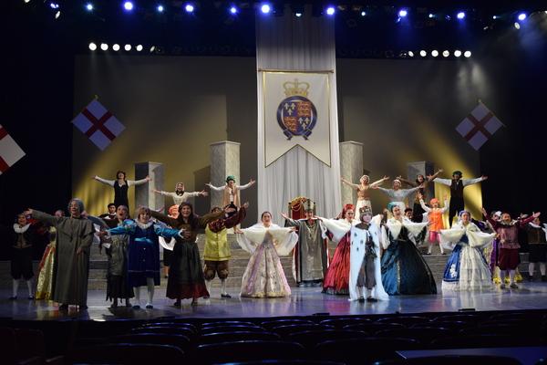 ステージ全体に広がり、両手を広げて踊っているたくさんの出演者の写真