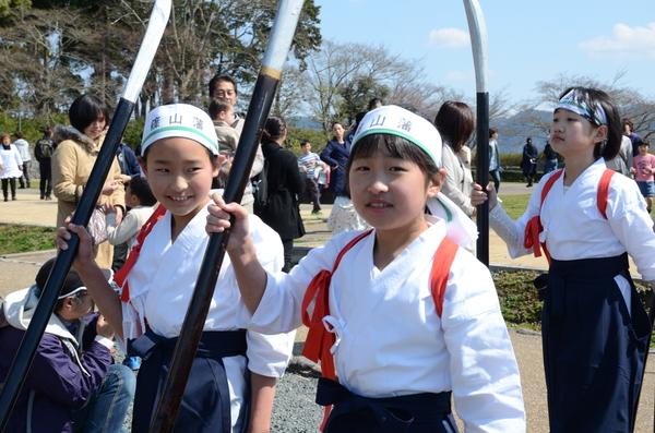 頭に篠山藩と書かれたハチマキをして手には大きな槍を持ち袴姿で歩いている写真
