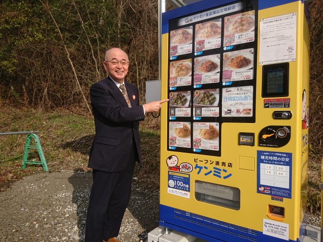 冷凍ビーフンの自販機を指さす市長