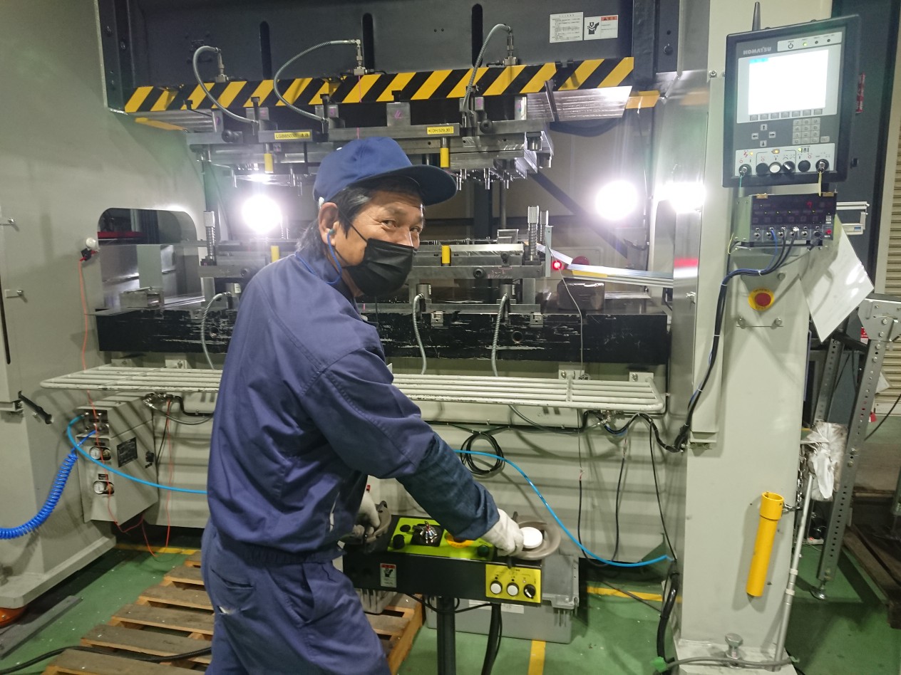 機械の前で振り返っている作業着を着た男性