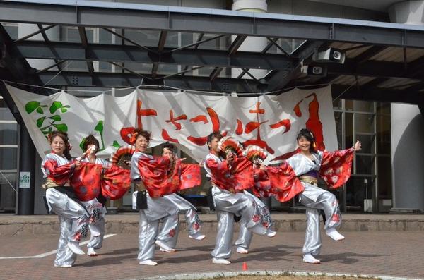 扇子と真っ赤な衣装の7名でポーズをとっている写真