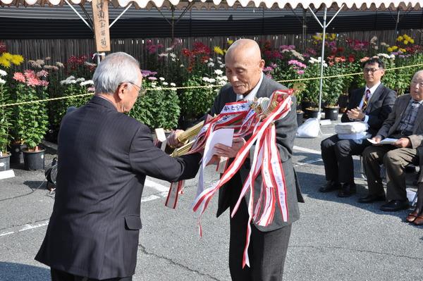 青山賞で、福井 邦準さんがトロフィーを受け取っている写真