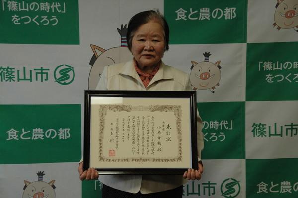 「恩賜財団母子愛育会会長表彰」授与され表彰状を両手に持った小島さんが緊張の面持ちの写真