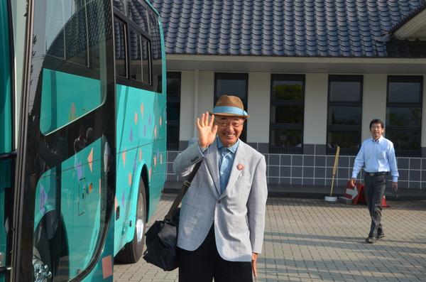 マイクロバスの前で市長が笑顔で手を振っている写真