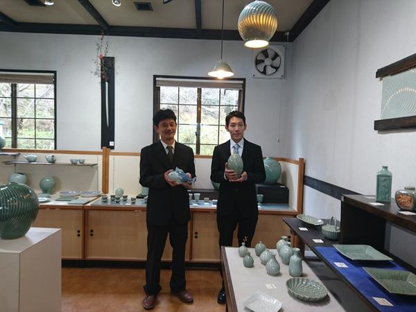 王地山焼展示場所で竹内 保史さん、児玉 玲央奈さんが焼き物を持っている写真