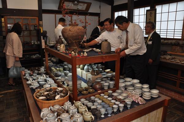 急須や湯吞などの色々な産地の焼き物が並べられているのを見ている人々の写真