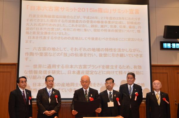 スクリーンの前で市長と男性5名が立ち、市長が代表でお話ししている写真