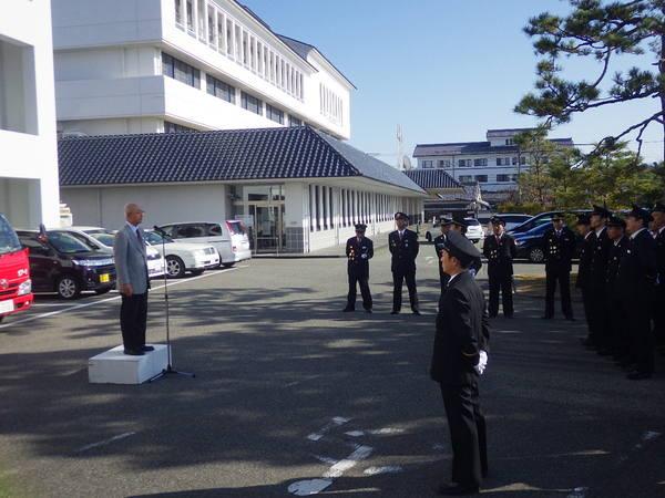 消防車の引渡式で市長が挨拶しているのを消防団員が聞いている写真