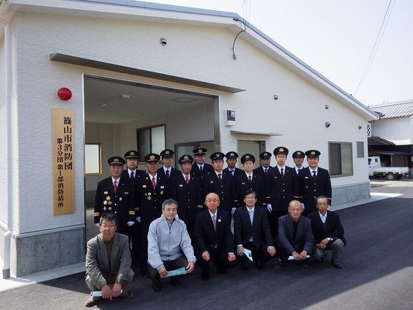完成した消防詰所兼車庫の前で市長と消防団員で記念撮影している写真