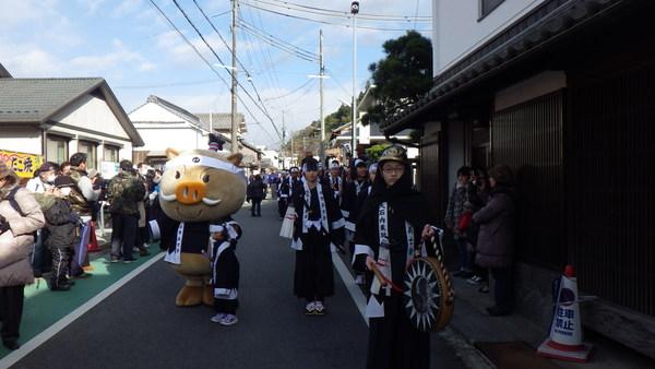 子ども義士行列が太鼓をたたきながら、まるいのと崇元寺周辺を歩いている写真
