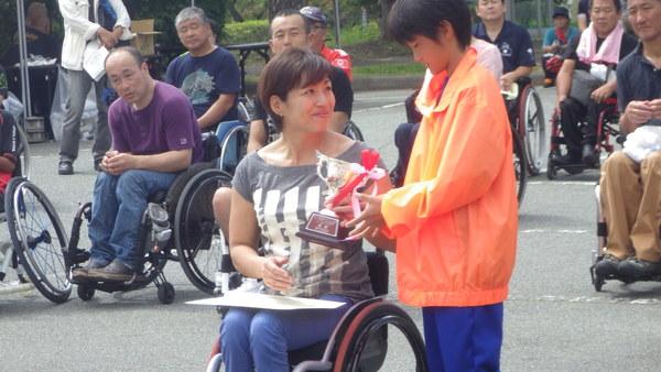 土田さんが子どもから優勝のトロフィーを受け取っている様子の写真