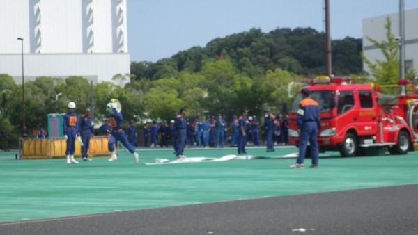 消防団員が、消防車からホースを引いて走りだしている訓練の様子の写真