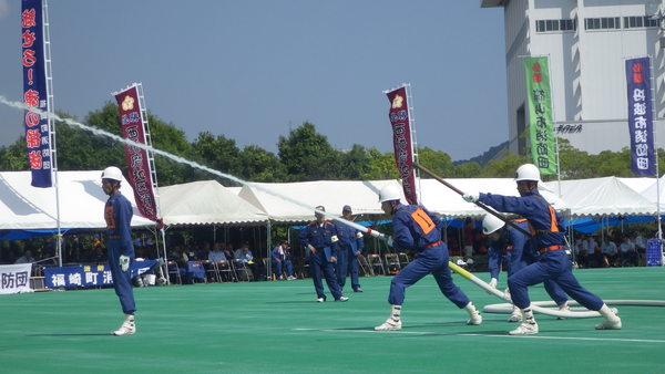 消防団員がホースを構え、ホースから水が噴き出している様子の訓練の写真
