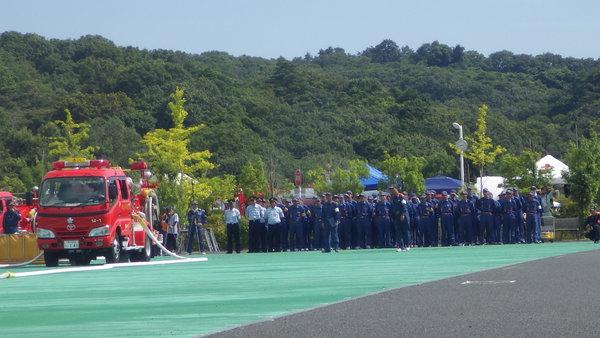 消防車の後方に消防団員が整列している様子の写真