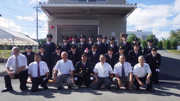 消防詰所の前で制服姿の消防団員らが市長らと記念撮影している写真