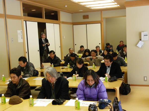 台湾の屏東県(へいとうけん)から視察に来られた24名が、和室に並べられた長机に4名ずつ座っており、机にはお茶と資料が置かれ参加者が資料に目を通している様子の写真