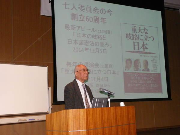 プロジェクトスクリーンの前で話す、物理学の小沼 通二先生の写真