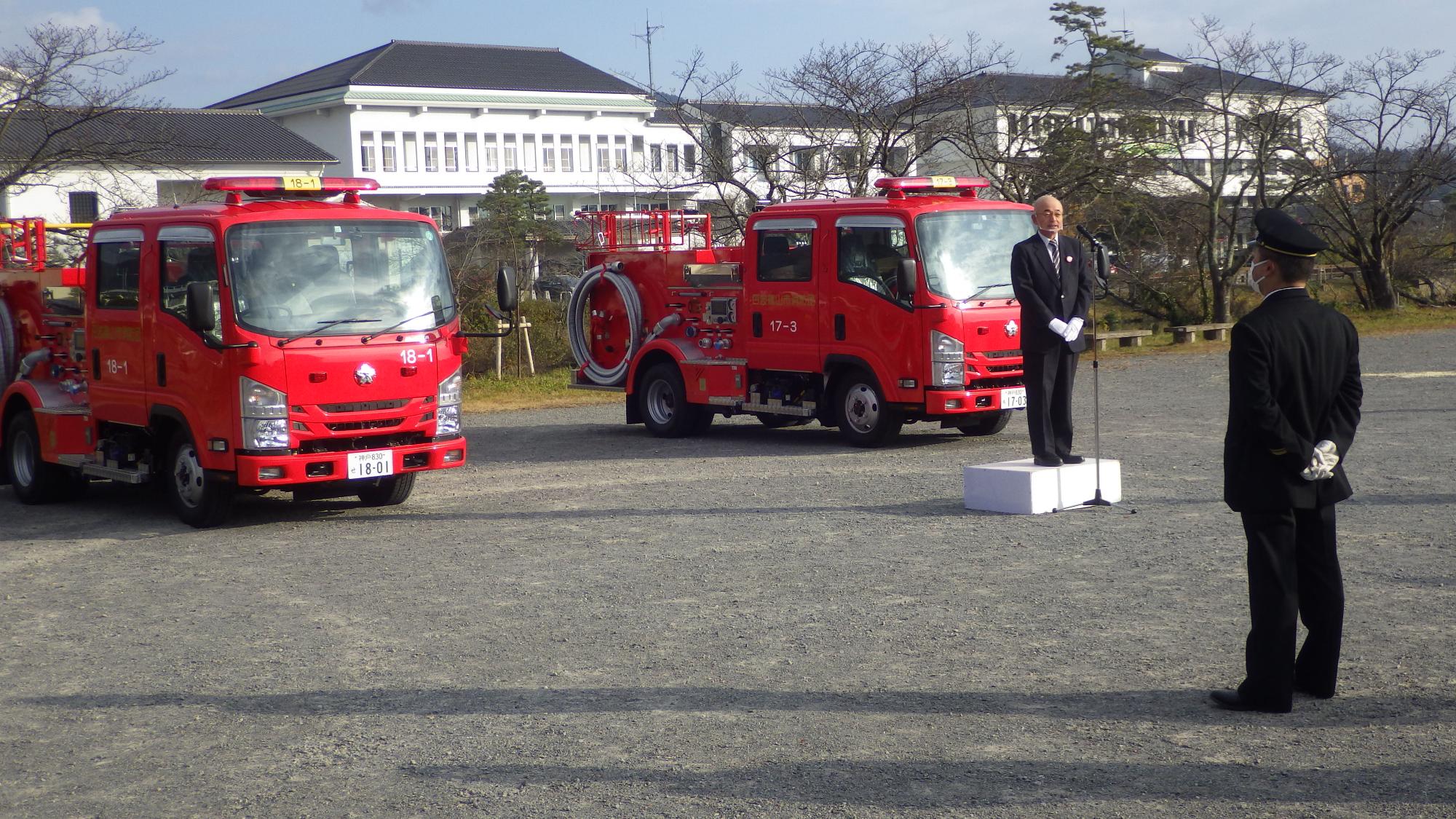三の丸広場で、消防団に新しく引き渡す車両の前で酒井市長が団員に話されている。