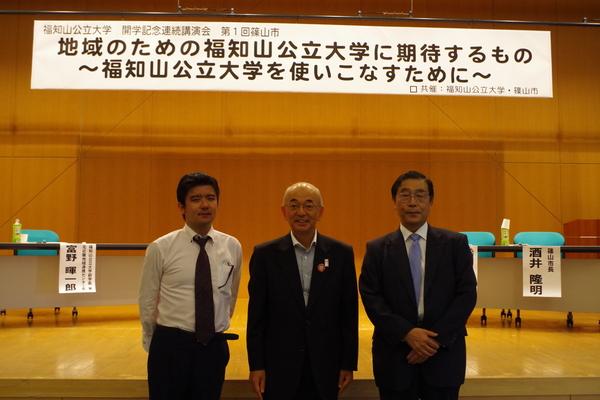 第一回福知山公立大学開学記念講演会に参加して富野暉一郎さん、嶋田さん、市長が舞台の下にたち3人で記念写真