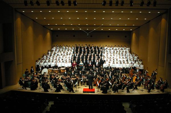 前方にはオーケストラが演奏し、後方には大勢のコーラスの方が隙間なく段々に並んでいる様子の写真