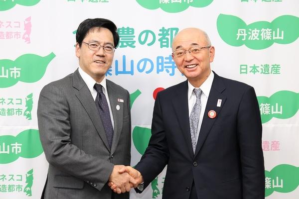 坂野局長と市長が握手をして写っている写真