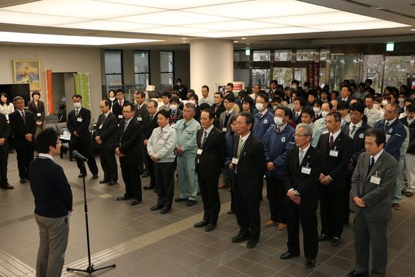 職員に向かって挨拶する山本さんと整列して両手を前に組んで話を聞いている職員たちの写真