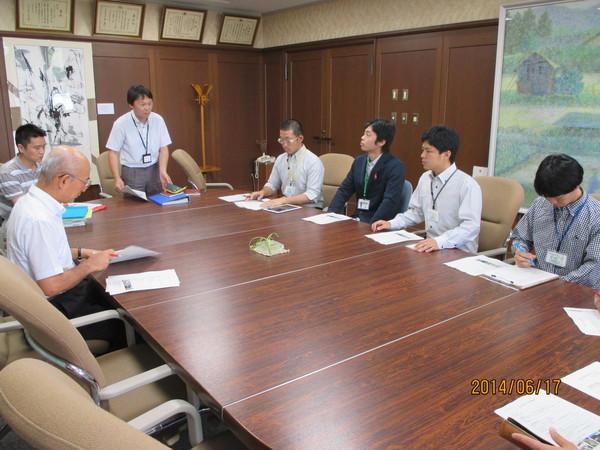 市長と地域おこし協力隊のメンバーが集まり、男性が立って話をしている写真