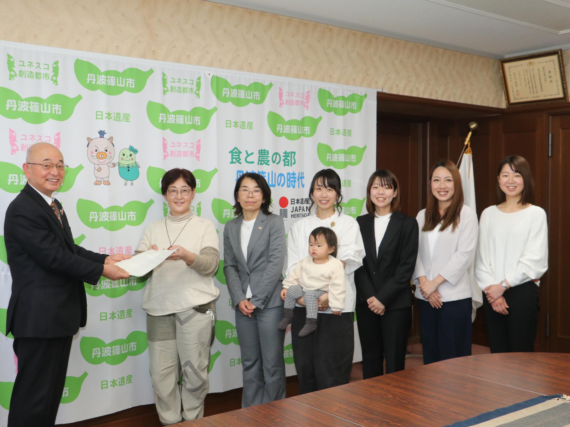 女性委員会の皆さんが並んで市長に報告書を手渡しされている