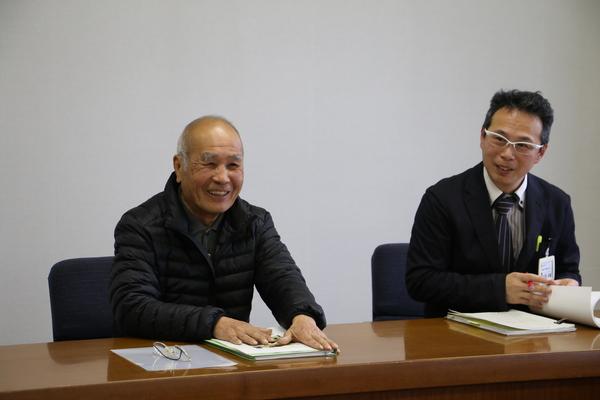 笑顔で着席している平野 正憲さんとその横に座る男性の写真