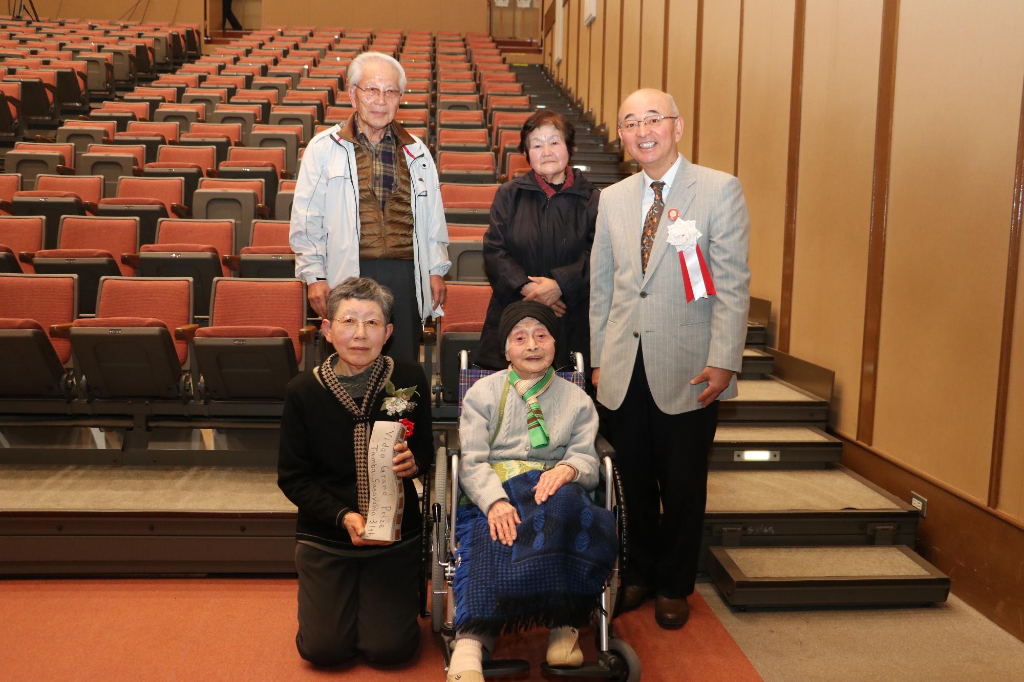 車いすに乗った長澤さんと、その横に膝をたてて座る阪下さんなどの写真