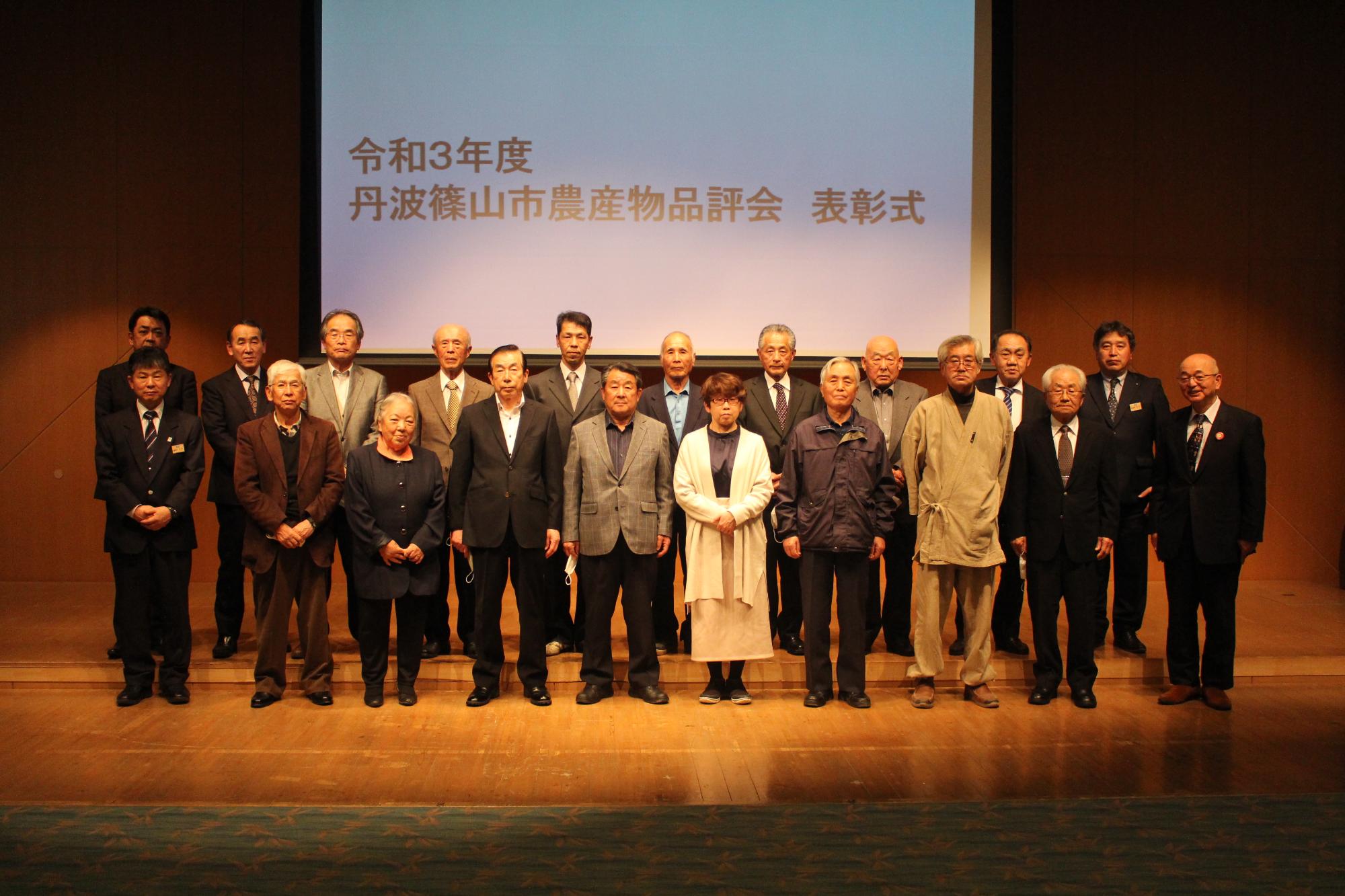 舞台の上で、受賞者が2列に並んで立っている