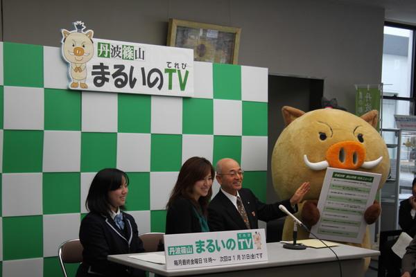 パなエルを持ち立っているまるいのと笑顔でテレビ出演している上野杏さん、司会の松岡美穂さんと市長の写真