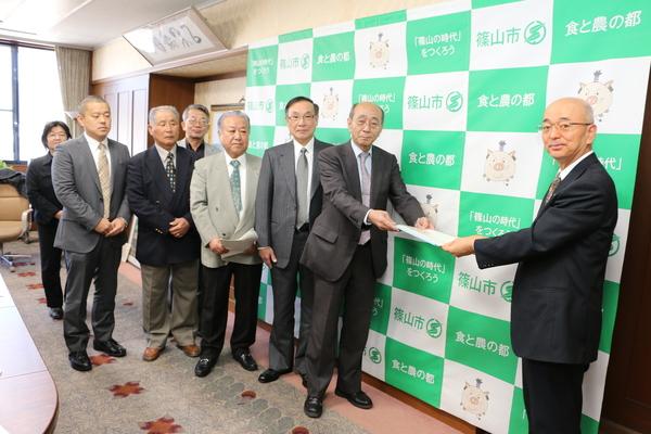 中川委員長が市長へ書類を渡していて、西潟副委員長、太期委員、杉尾委員、森口委員、團野委員、澤山委員と集合写真