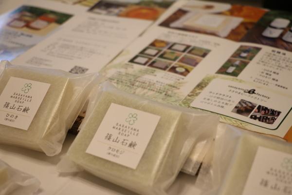パンフレットの上に、半透明の洗練された包装に入れられ「篠山石鹸 」と書かれている四角い石鹸の写真