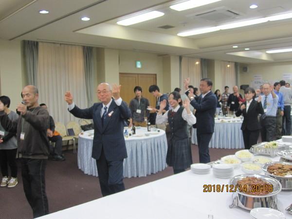 テーブルに料理がならべてあり、その横で市長や、他の参加者達が縦に並んで踊っている写真