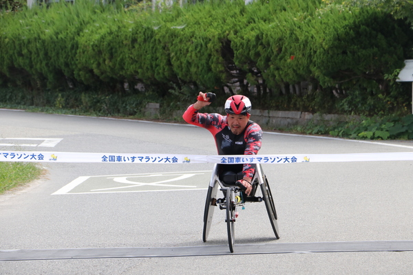 車いすマラソンでガッツポーズしてゴールしている
