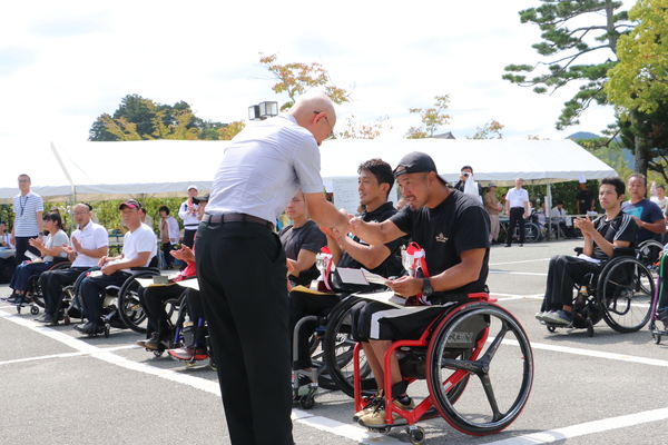 車いすマラソンの表彰式。市長と選手が握手している。