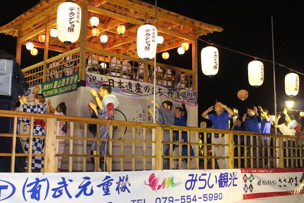 やぐらの上で、浴衣を着て踊る外国人男女の写真