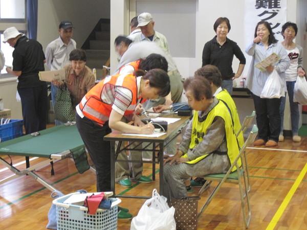 体育館で行われている古市地区防災訓練にて血圧測定を受けている高齢者2名の写真