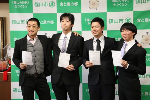 「地域おこし協力隊」に任命された菅原 将太さん、瀬戸 大喜さん、長井 拓馬さん、野口 陽平さんが任命書を手に肩を組みながら記念撮影している写真