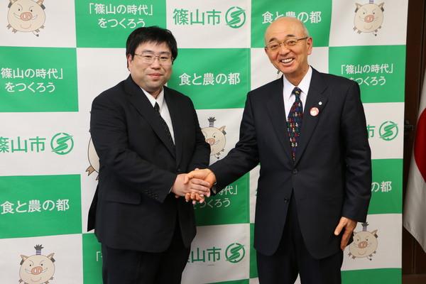 山本 憲康医師と市長が笑顔で握手をして写っている写真