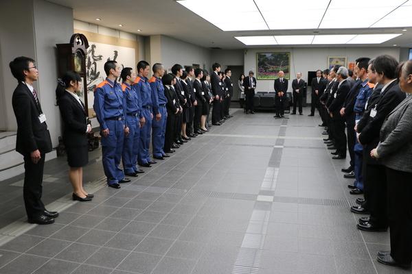 21名の新入社員の方が市長や関係者の方と向かい合って並んでおり、その中央前方にて市長が話をしている写真