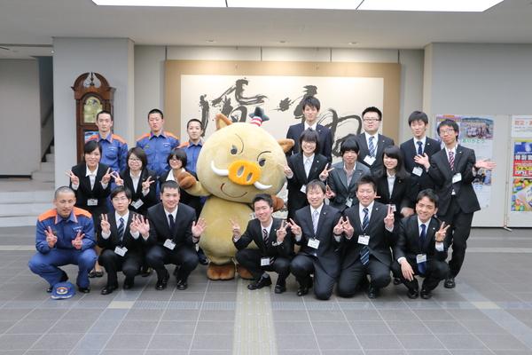 ロビーにてピースサインをしている新入社員の方々と、まるいのが記念撮影している写真