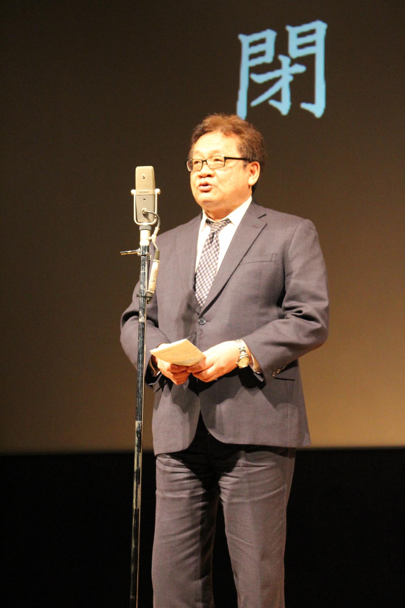 メインコメンテーターの石原先生がスタンドマイクを使い、閉会のあいさつをしている写真