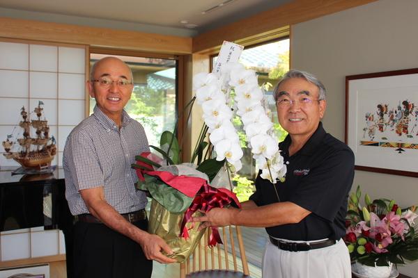 胡蝶蘭を持って記念撮影をする市長と金出さんの写真