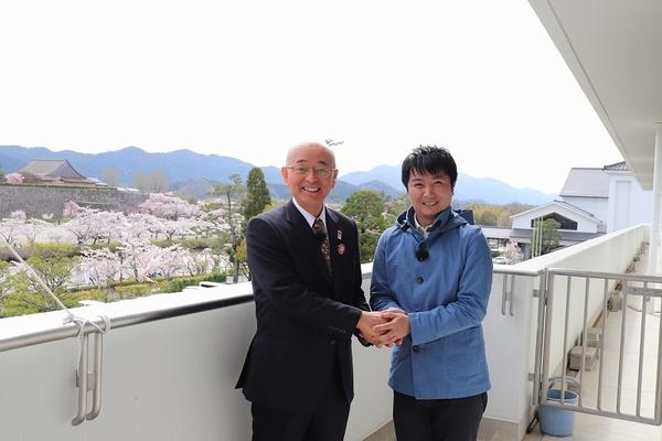 市長室のバルコニーで市長と気象予報士の広瀬さんが握手をしている写真